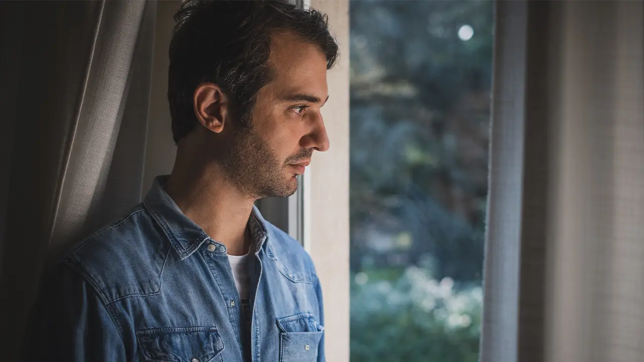 Man staring out of the window, looking forlorn