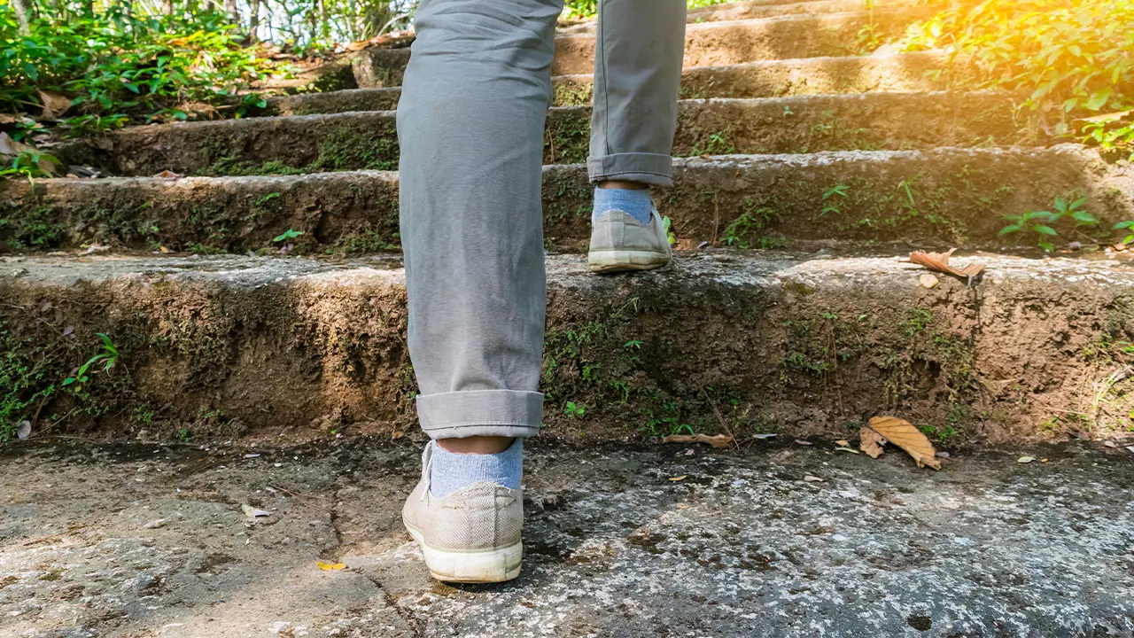 Person walking up stone stairs outside, zooming in on their legs and feet