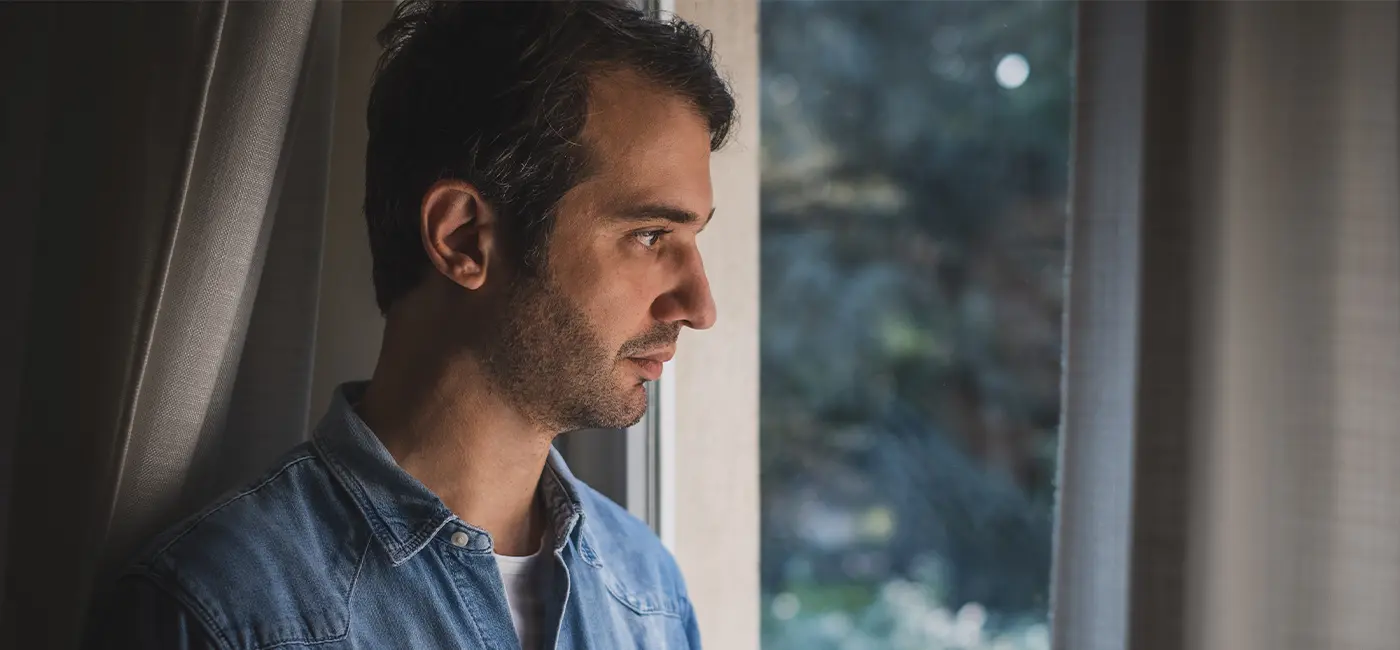 Man staring out of the window, looking forlorn