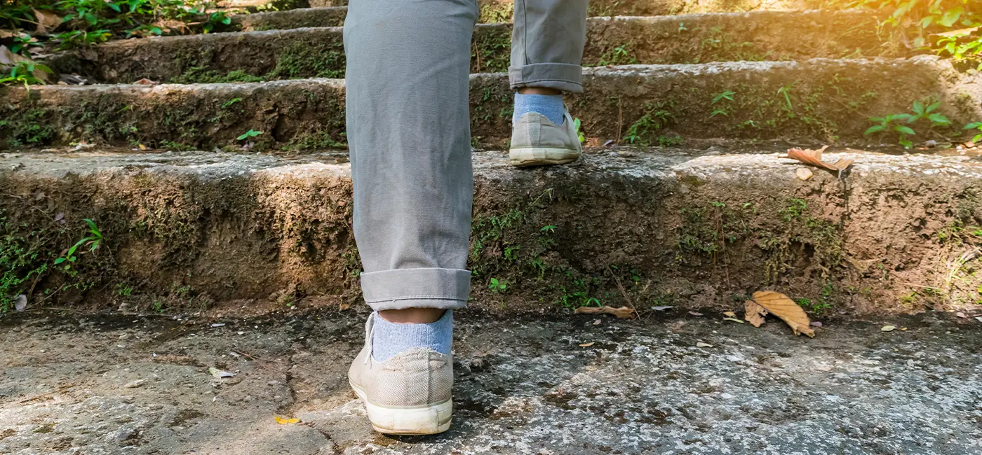 Person walking up stone stairs outside, zooming in on their legs and feet