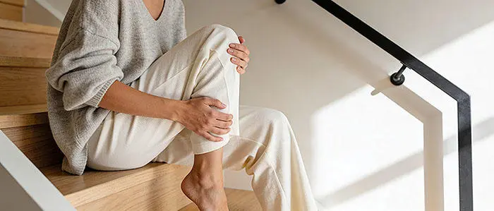 woman on stairs holding leg in pain
