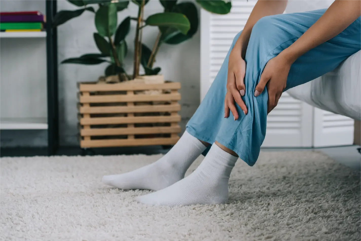 Woman on edge of bed holding leg