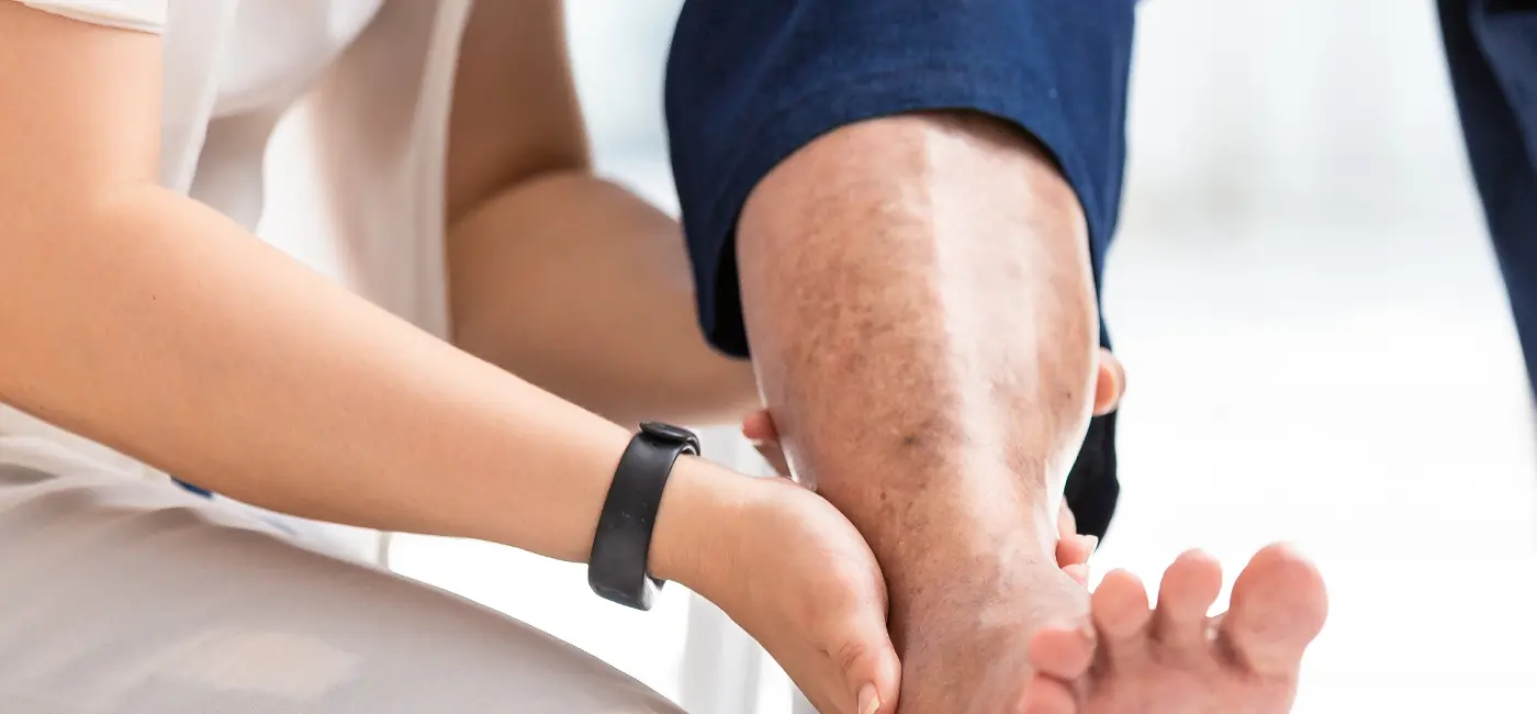 Doctor checking leg of elderly woman