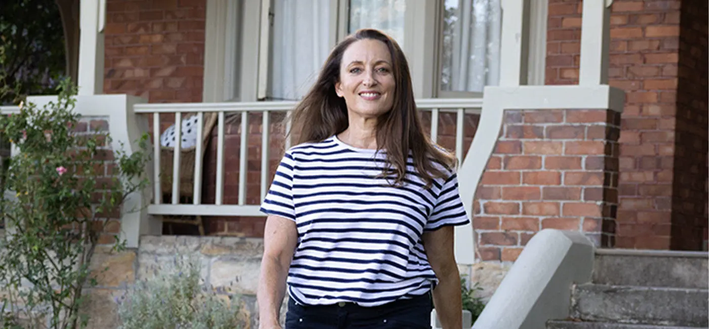 Image of Georgie outside a house walking towards the camera smiling