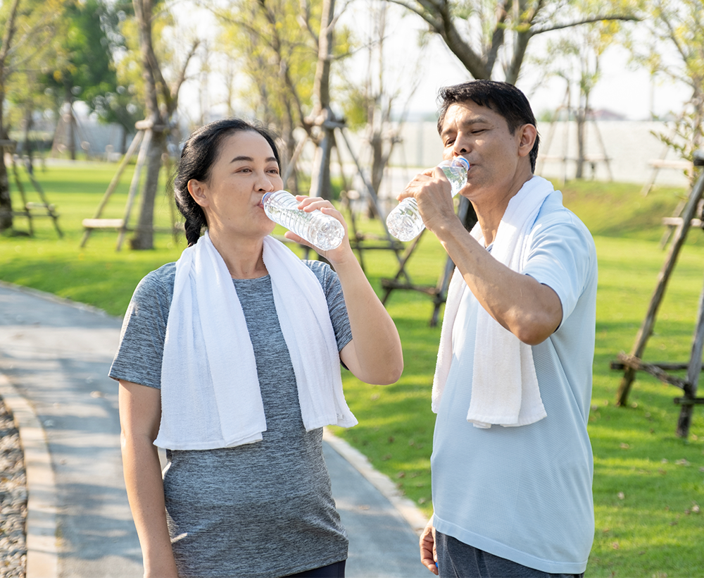 Couple out on a run in a park, they've stopped to drink water