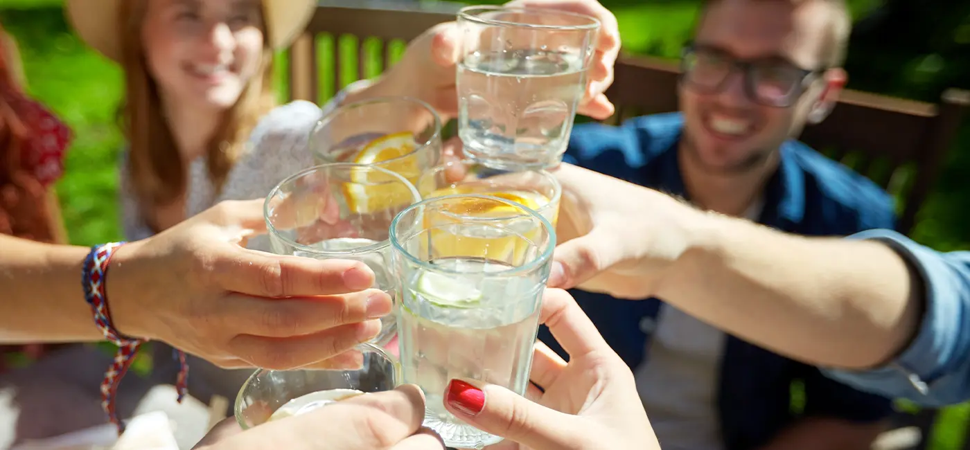 Gros plan sur un groupe de mains qui trinquent avec des verres d'eau.