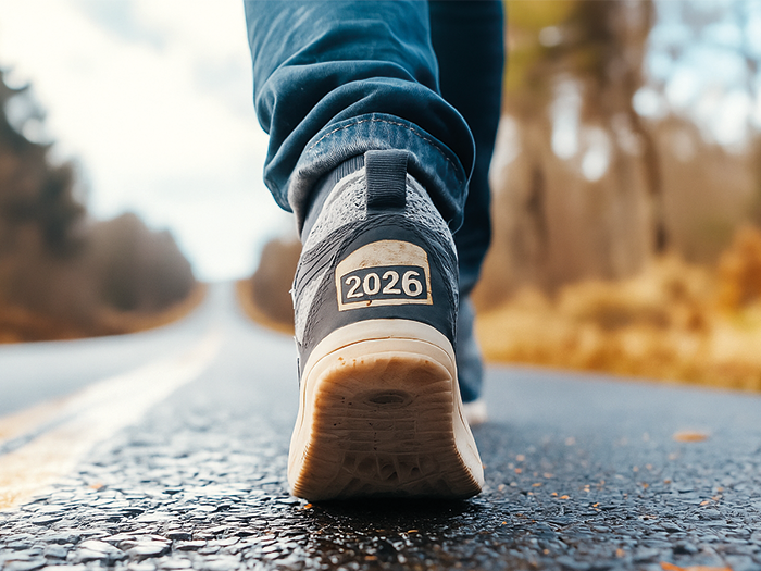 Close up of legs walking on a road, back of trainer labelled with 2026