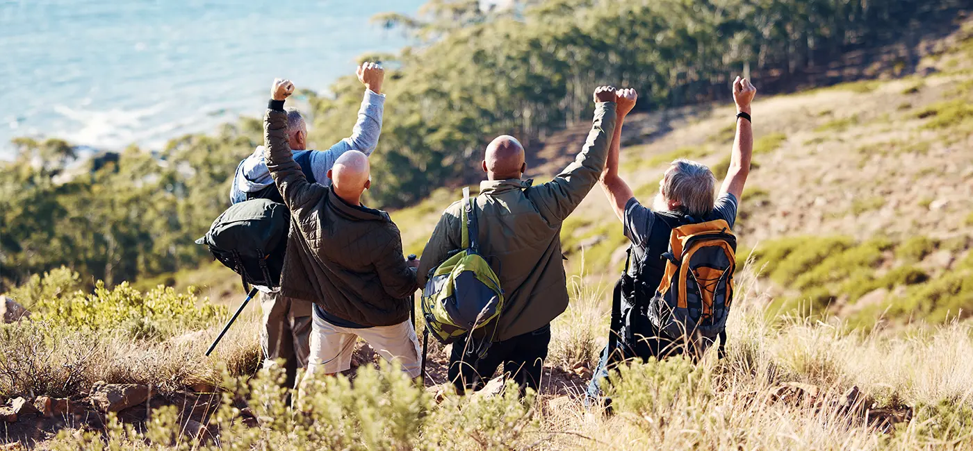 Four men standing on the top of a hill looking at the views and celebrating