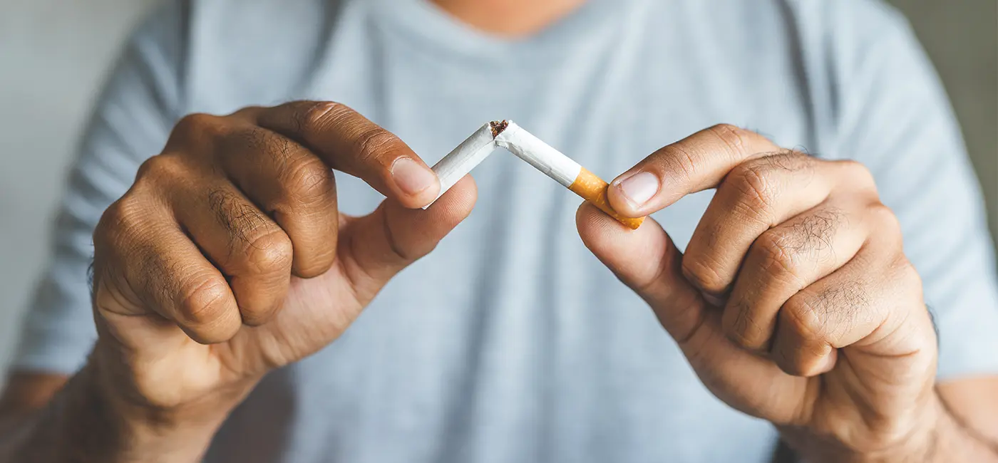 Man holding the ends of a cigarette, breaking it in half