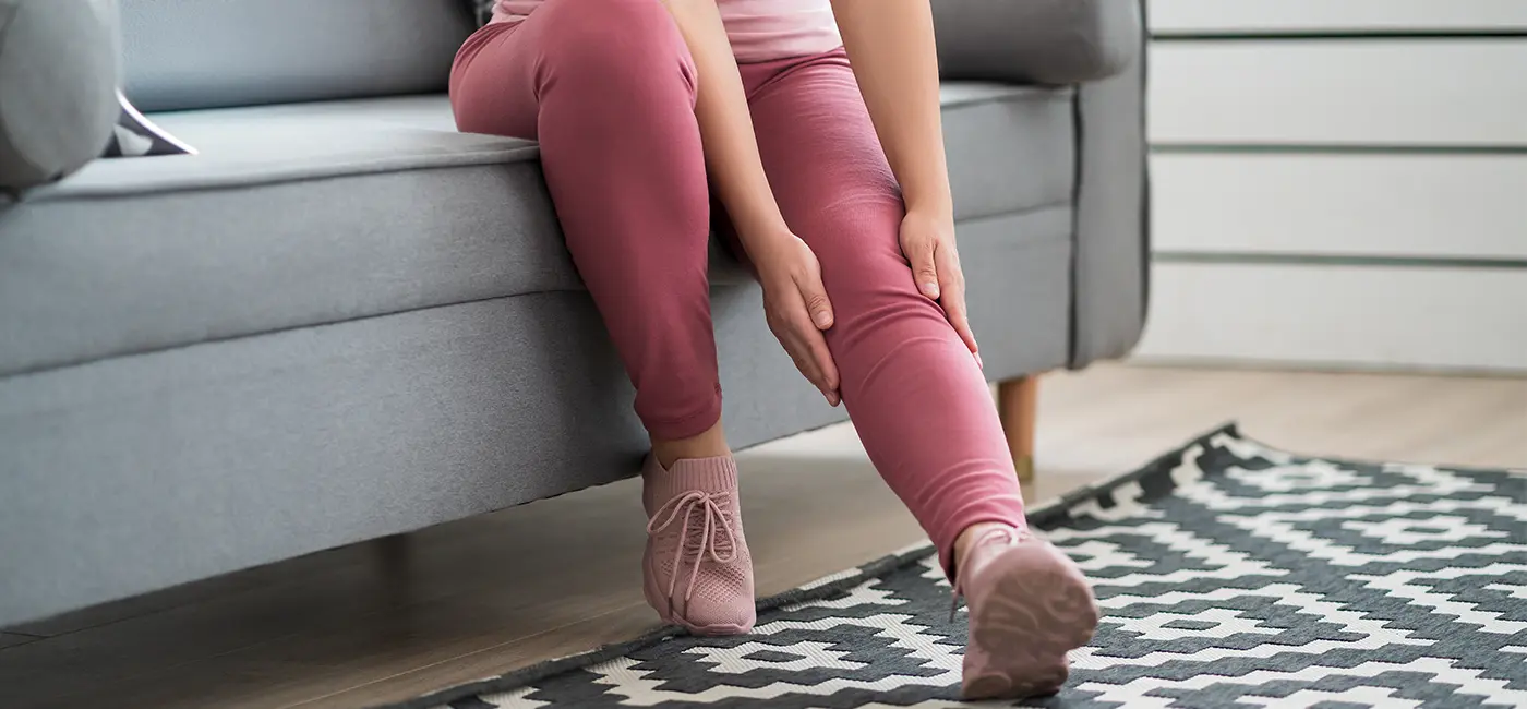 Woman sat on her sofa holding the sides of her knee