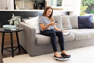 Georgie sat on the sofa using a device while looking at her phone