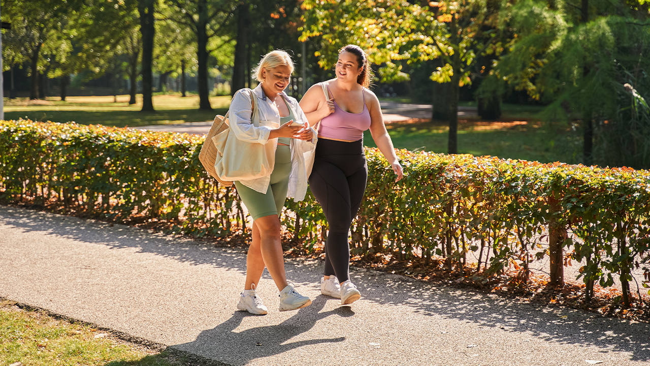 A middle-aged woman walks through a green park.