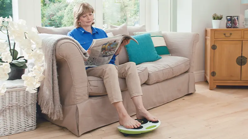 A woman relaxing on the couch whilst using Revitive