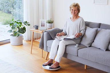 donna con i piedi su un dispositivo che legge una rivista