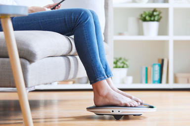 Person with their feet on a coach device while using the app on their phone