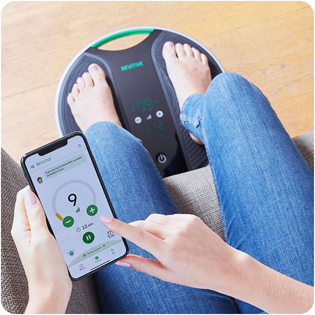 Close up on a womans feet on a coach device while holding her phone 