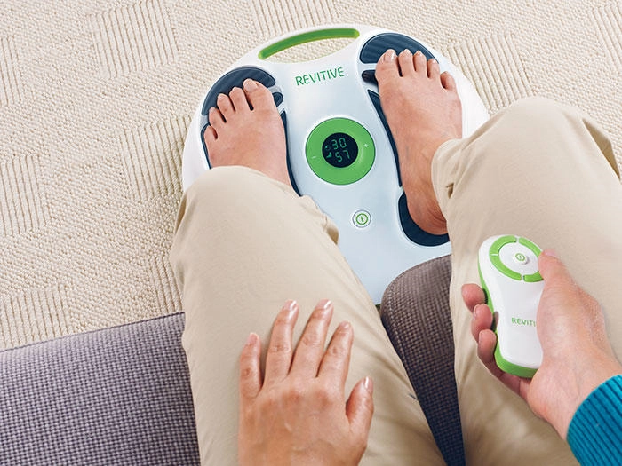 Woman sat down using the prorelief device with the remote in her hand