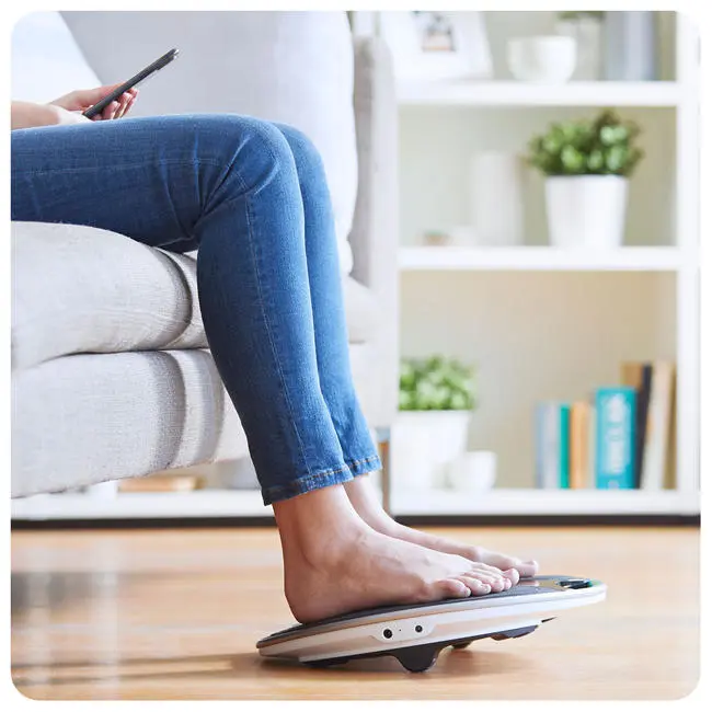 Close up on a womans feet on a coach device while holding her phone
