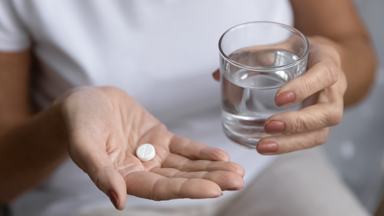 Image on a woman holding a tablet and glass of water