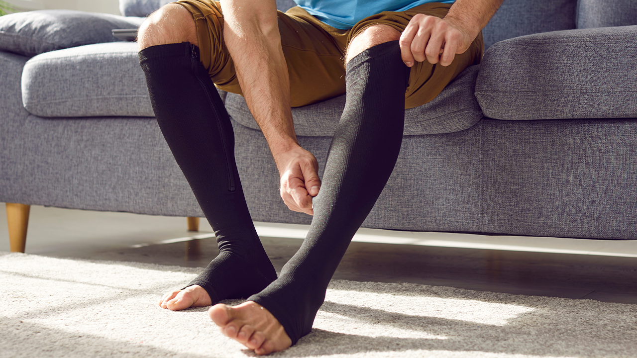 Image of a man putting on compression socks 