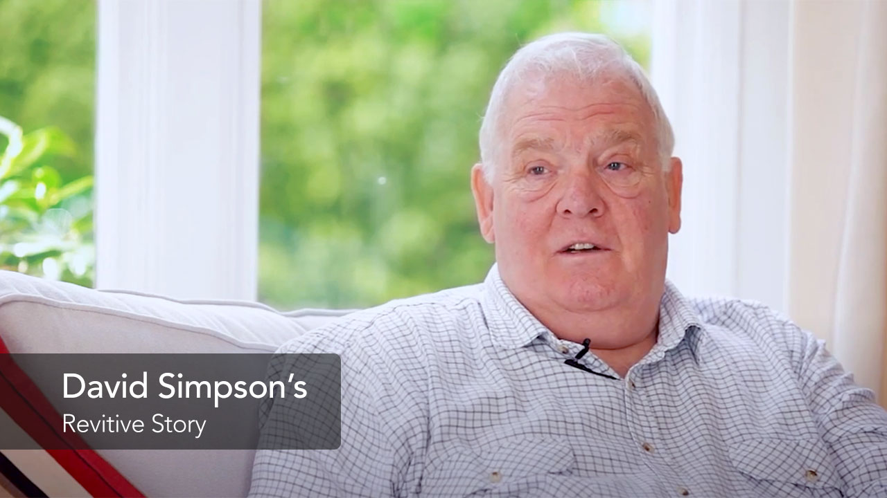 David a Revitive customer sat on his sofa looking at the camera 