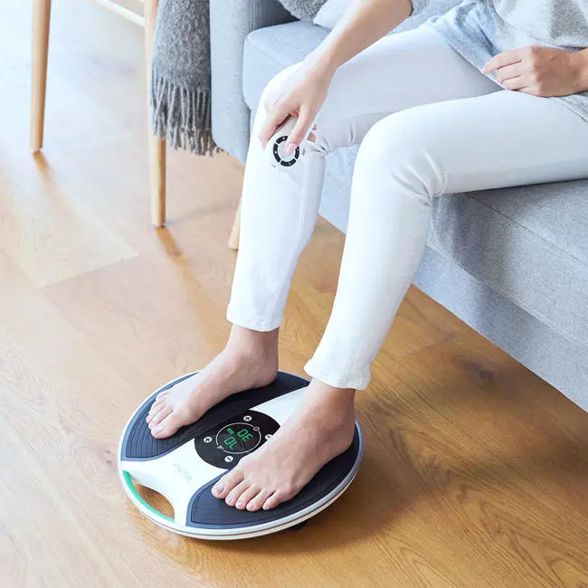 close up image of lady with her feet on the medic device holding the remote