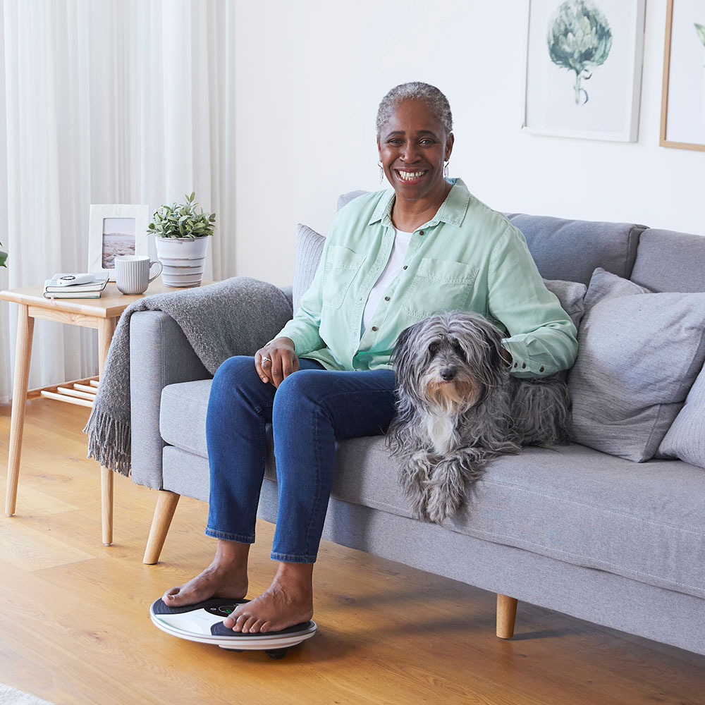 Image of woman and her dog. woman has her feet on the medic decive 